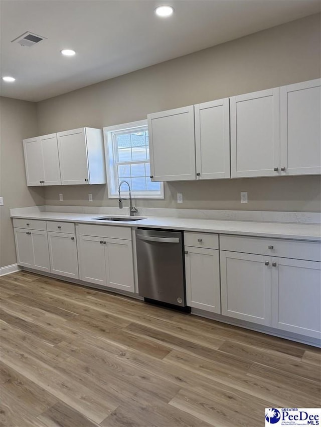 kitchen featuring sink, stainless steel dishwasher, white cabinets, and light wood-type flooring