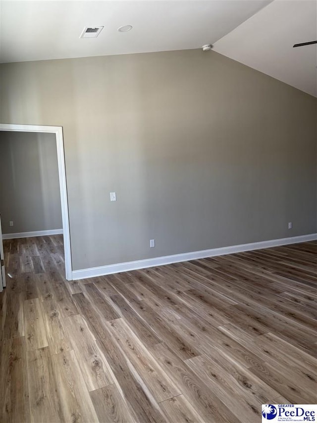 spare room with wood-type flooring and lofted ceiling