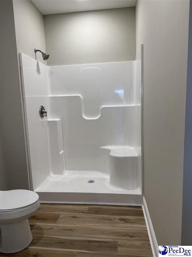 bathroom with hardwood / wood-style flooring, toilet, and walk in shower