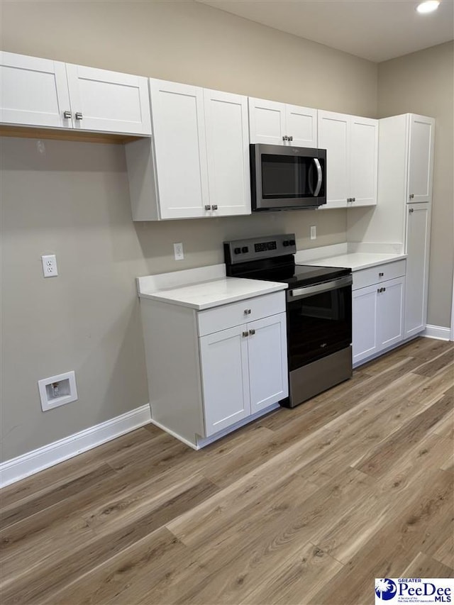 kitchen with light hardwood / wood-style floors, white cabinets, and appliances with stainless steel finishes