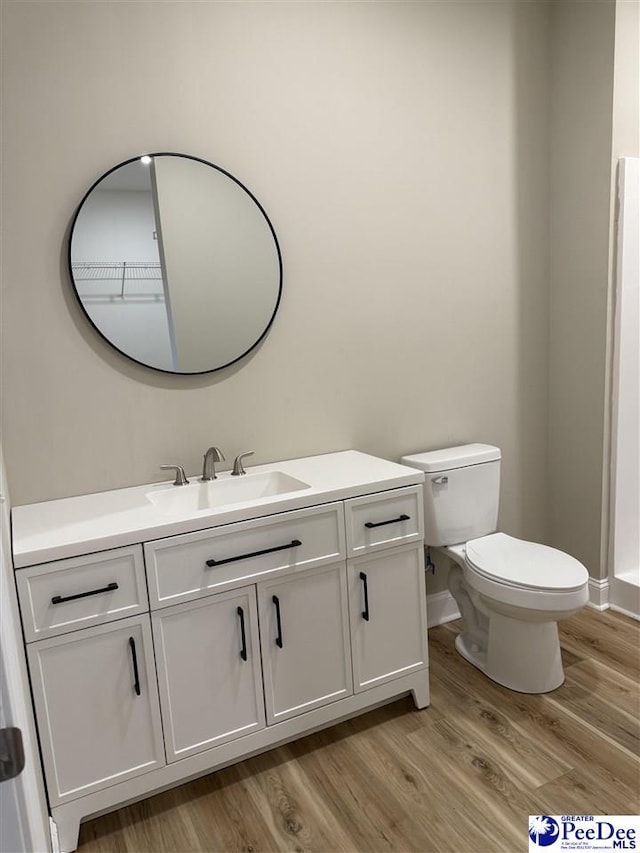 bathroom featuring wood-type flooring, toilet, and vanity