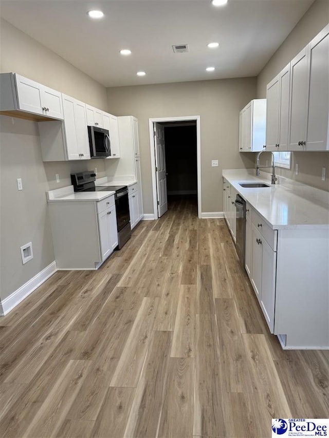 kitchen featuring light wood-type flooring, stainless steel appliances, sink, and white cabinets