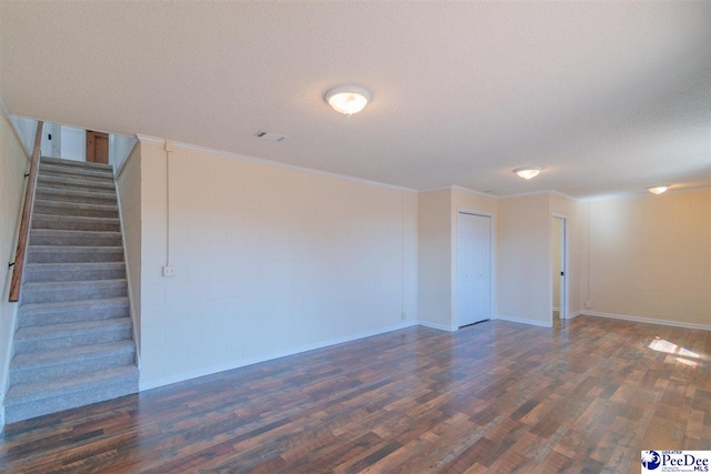 interior space featuring stairs, ornamental molding, dark wood-style floors, and a textured ceiling