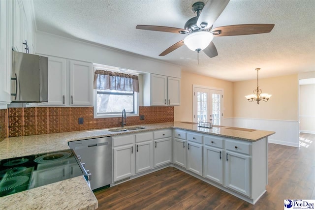 kitchen with a peninsula, decorative backsplash, dishwasher, a sink, and a textured ceiling