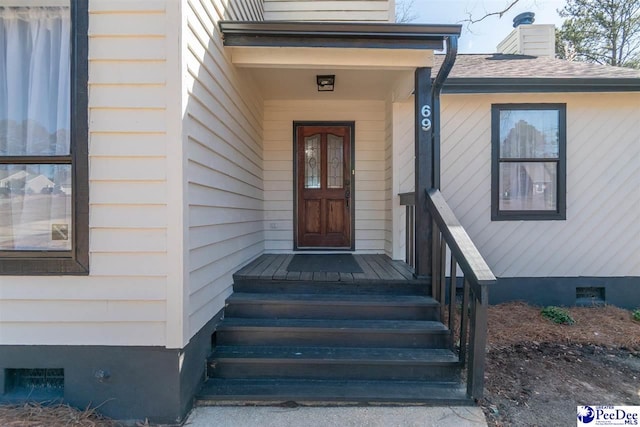 property entrance with a shingled roof, a chimney, and crawl space