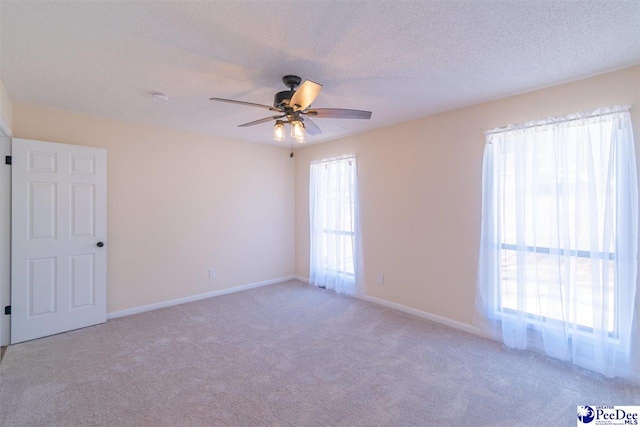 empty room with baseboards, light colored carpet, a textured ceiling, and ceiling fan