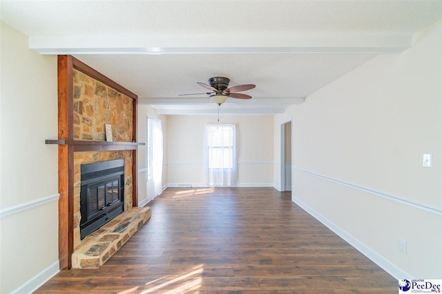 unfurnished living room with wood finished floors, baseboards, a fireplace, a textured ceiling, and beamed ceiling