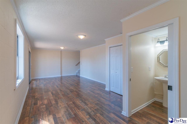 spare room featuring a textured ceiling, crown molding, stairway, dark wood-style floors, and baseboards