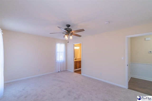 unfurnished bedroom featuring carpet, baseboards, ensuite bathroom, and ceiling fan