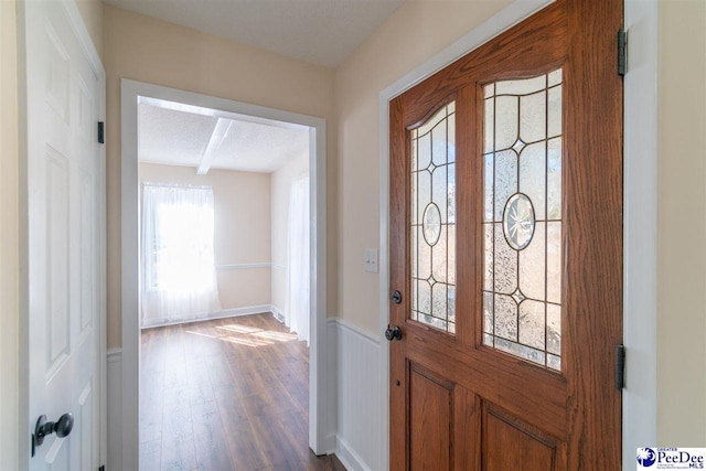 entrance foyer featuring dark wood-style floors and wainscoting