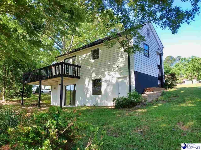 back of property with a wooden deck and a lawn