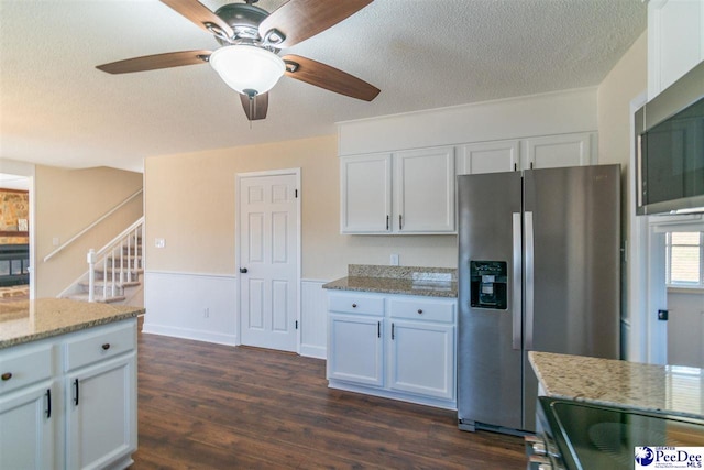 kitchen featuring light stone counters, a textured ceiling, white cabinets, stainless steel appliances, and dark wood-type flooring