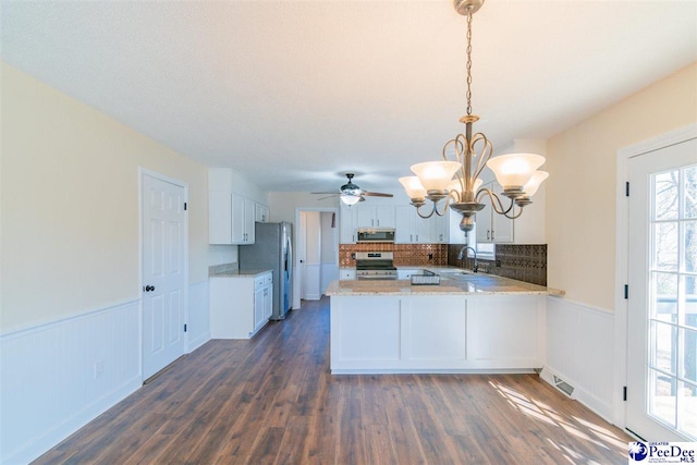 kitchen with visible vents, a wainscoted wall, appliances with stainless steel finishes, a peninsula, and a sink