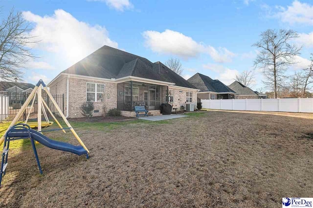 rear view of property with cooling unit, a patio area, a sunroom, and a playground