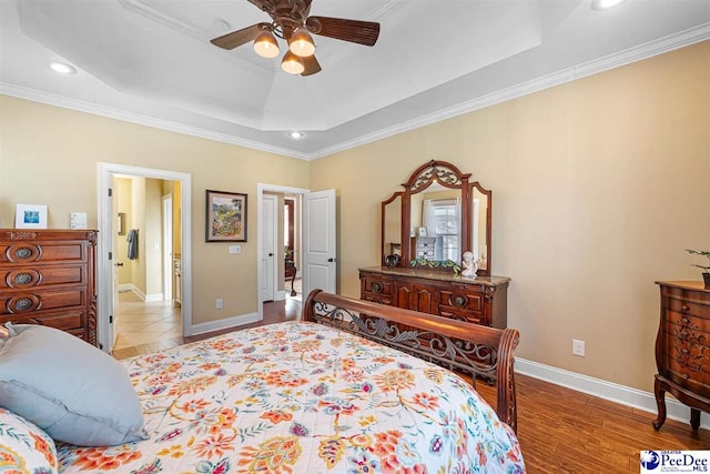 bedroom featuring a raised ceiling, crown molding, ceiling fan, and light wood-type flooring