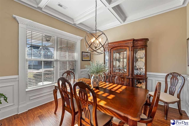 dining area featuring beamed ceiling, hardwood / wood-style flooring, ornamental molding, coffered ceiling, and an inviting chandelier