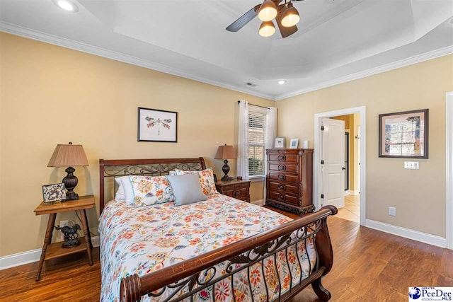 bedroom featuring crown molding, a tray ceiling, and hardwood / wood-style flooring