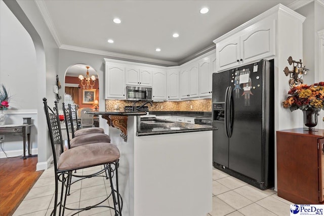 526 Shannon Rd, Marion, SC 29571 - kitchen featuring black fridge with ice dispenser, a chandelier, crown molding, stainless steel microwave, and a breakfast bar area