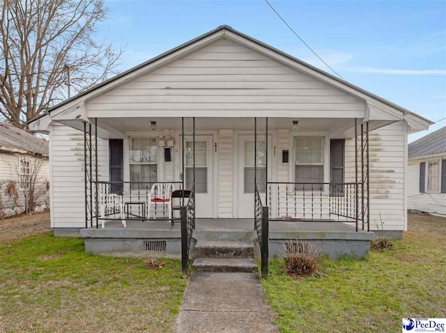 bungalow-style home featuring a front yard and covered porch