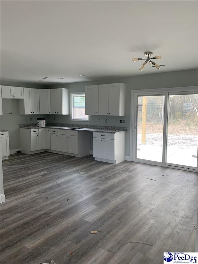 kitchen with dark wood-style flooring, stone counters, white cabinetry, and baseboards