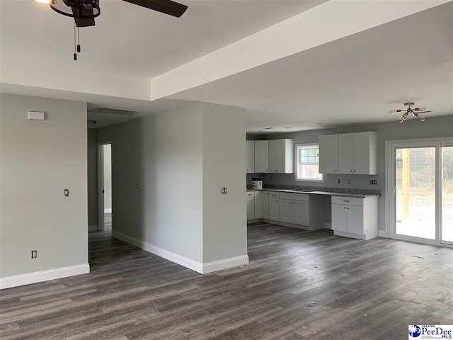 kitchen featuring light countertops, open floor plan, white cabinetry, and baseboards