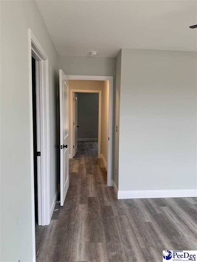 corridor with dark wood finished floors and baseboards