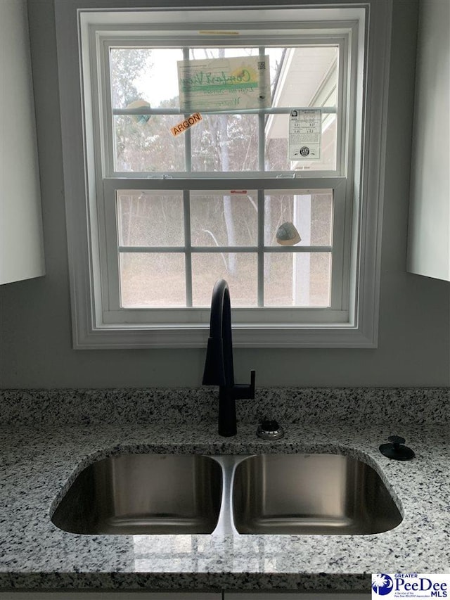 details with a sink and light stone countertops