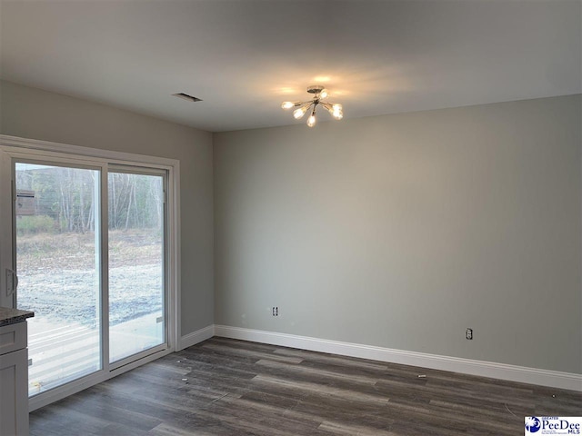 spare room featuring an inviting chandelier, dark wood finished floors, visible vents, and baseboards