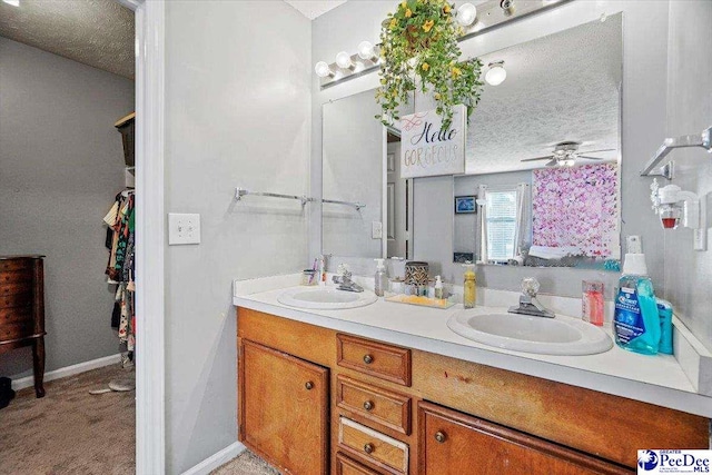 bathroom featuring vanity, ceiling fan, and a textured ceiling