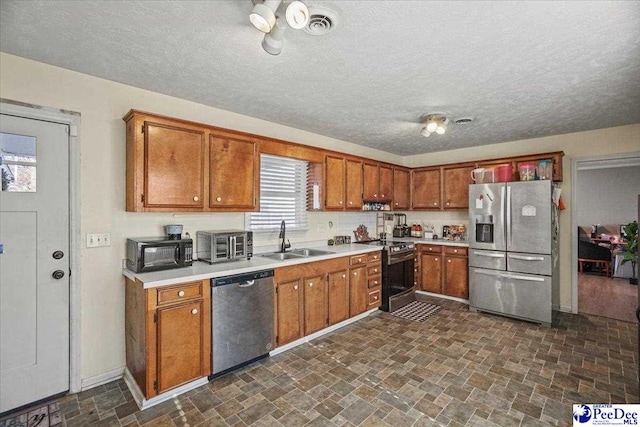 kitchen with sink, a textured ceiling, and appliances with stainless steel finishes