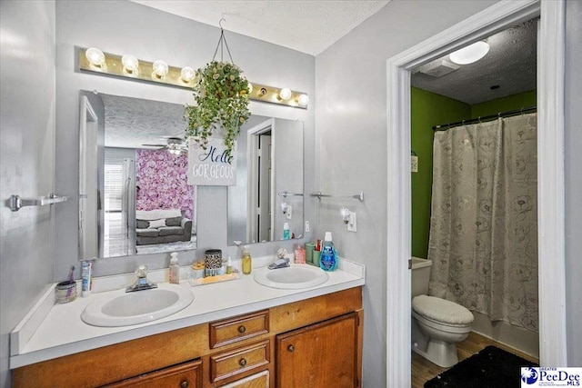 bathroom featuring ceiling fan, vanity, a textured ceiling, toilet, and walk in shower