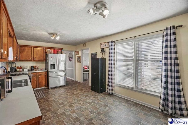 kitchen featuring stainless steel refrigerator with ice dispenser, sink, and a textured ceiling