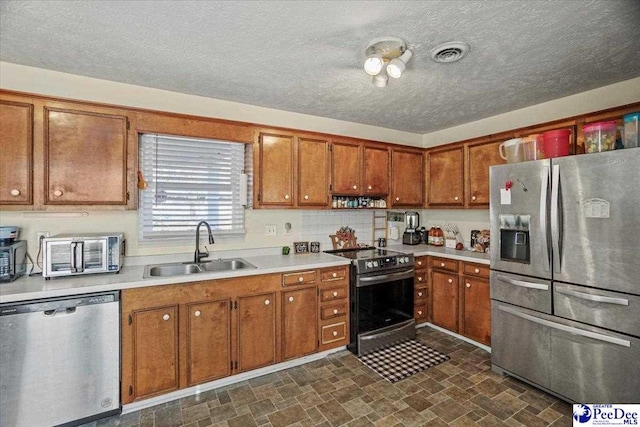 kitchen with appliances with stainless steel finishes, sink, and a textured ceiling