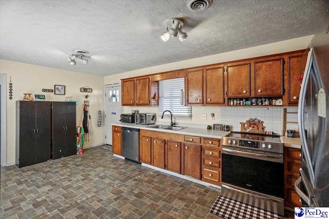 kitchen featuring tasteful backsplash, appliances with stainless steel finishes, sink, and a textured ceiling