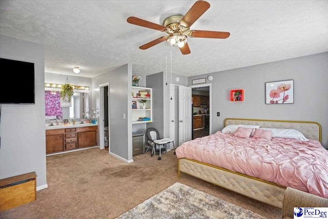 carpeted bedroom with ensuite bathroom, ceiling fan, and a textured ceiling