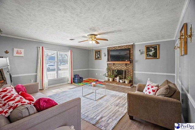 living room featuring ceiling fan, ornamental molding, light hardwood / wood-style floors, and a brick fireplace