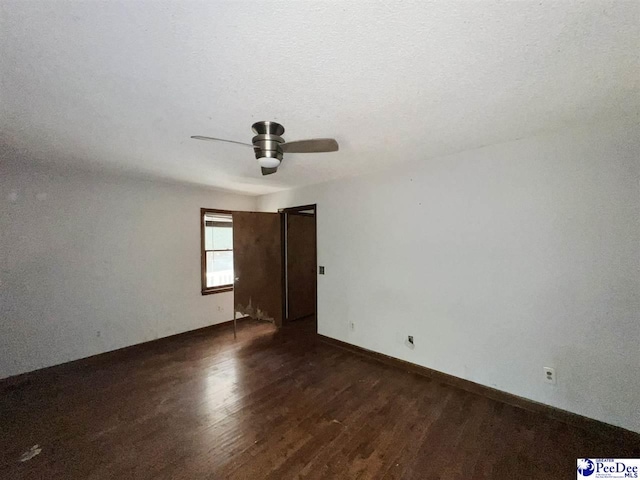 empty room featuring a textured ceiling, dark hardwood / wood-style floors, and ceiling fan