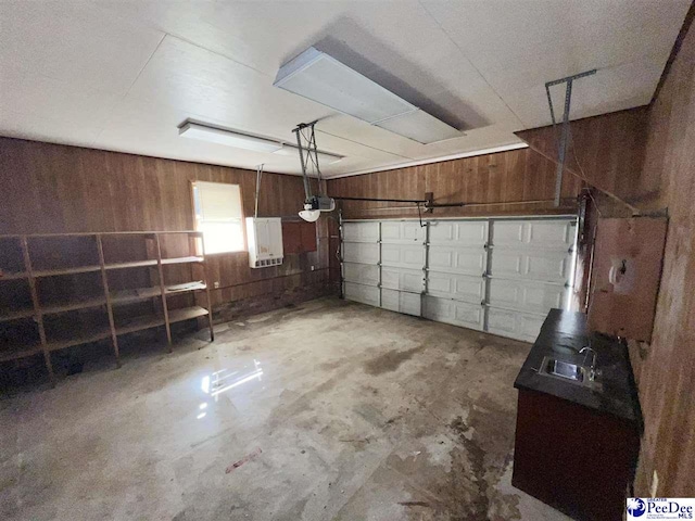 garage featuring a garage door opener, wooden walls, electric panel, and sink