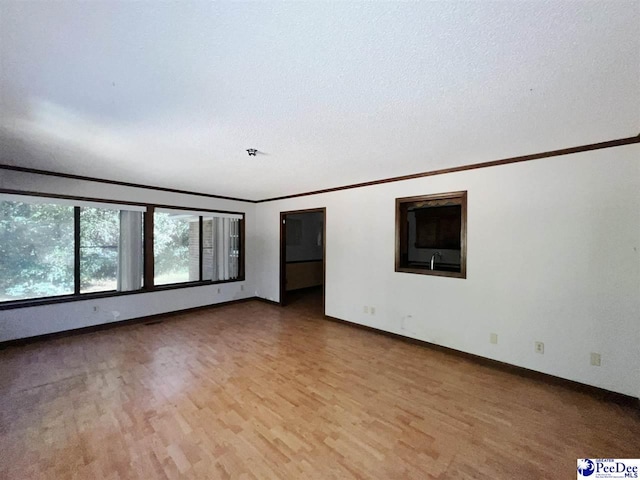 spare room with ornamental molding, a textured ceiling, and light hardwood / wood-style floors