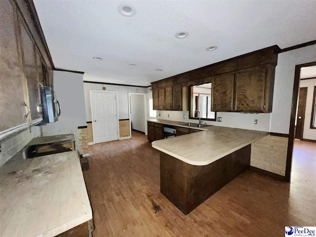 kitchen featuring sink, a breakfast bar area, dark wood-type flooring, ornamental molding, and kitchen peninsula