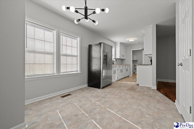 1933 3rd Loop Unit A, Florence, SC 29501 - kitchen featuring stainless steel fridge with ice dispenser, a chandelier, white cabinets, and baseboards