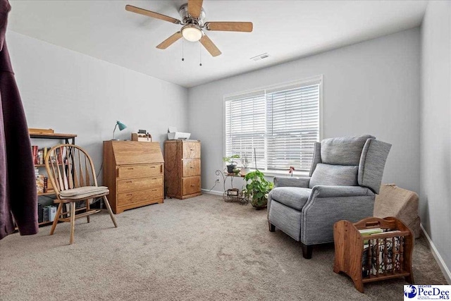 living area featuring baseboards, visible vents, a ceiling fan, and carpet flooring