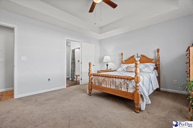 bedroom with carpet floors, a raised ceiling, baseboards, and a ceiling fan