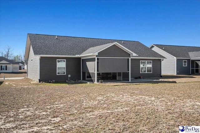 ranch-style house with a shingled roof and a patio area