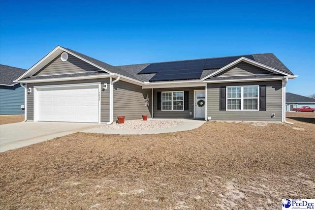 ranch-style house with a garage, solar panels, and driveway