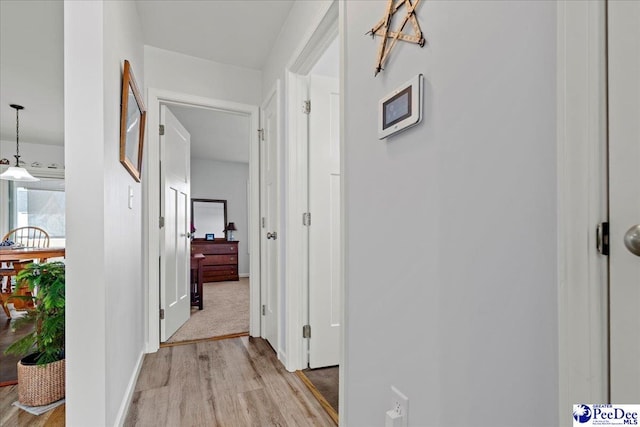 hall with light wood-style floors and baseboards