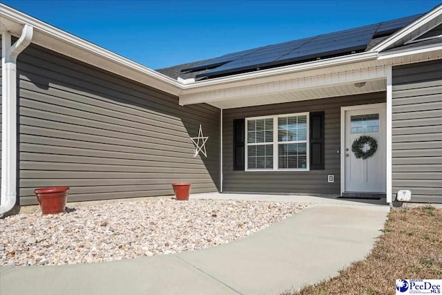 entrance to property with roof mounted solar panels and covered porch