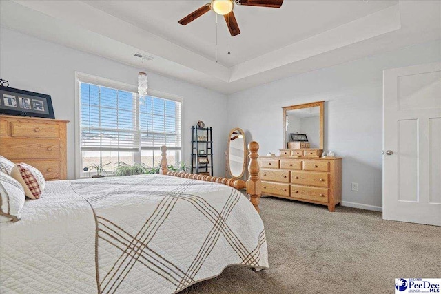 bedroom with ceiling fan, carpet flooring, visible vents, baseboards, and a raised ceiling