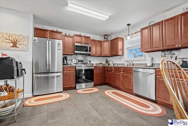 kitchen featuring appliances with stainless steel finishes, stone counters, brown cabinetry, and hanging light fixtures