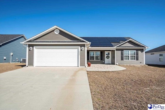 ranch-style house with a garage, solar panels, central AC, and concrete driveway